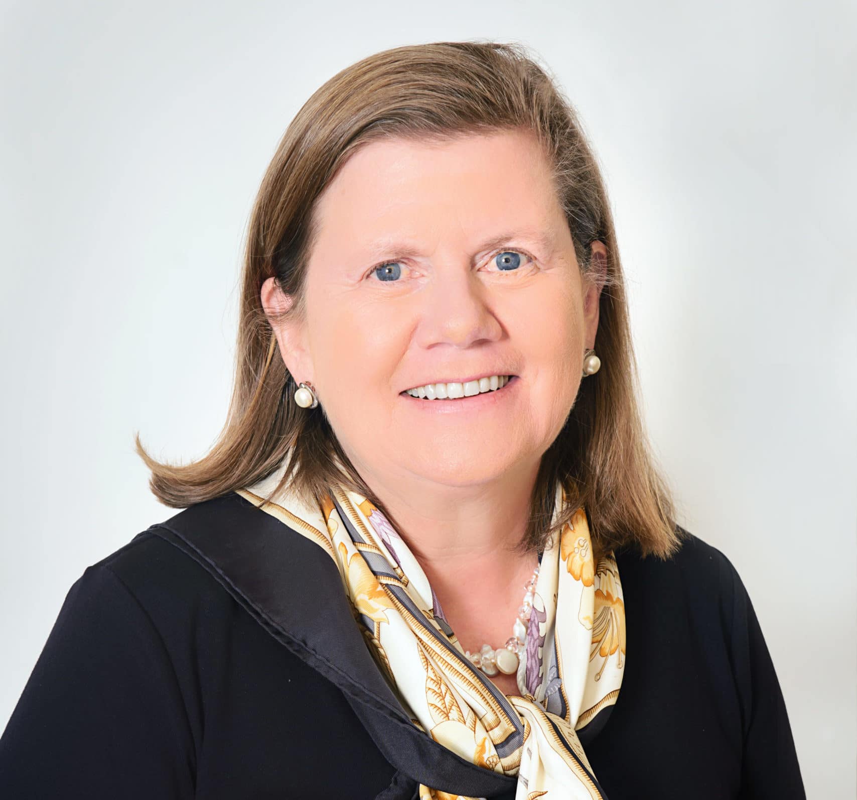 Picture of woman in a black top with a yellow and white patterned silk scarf