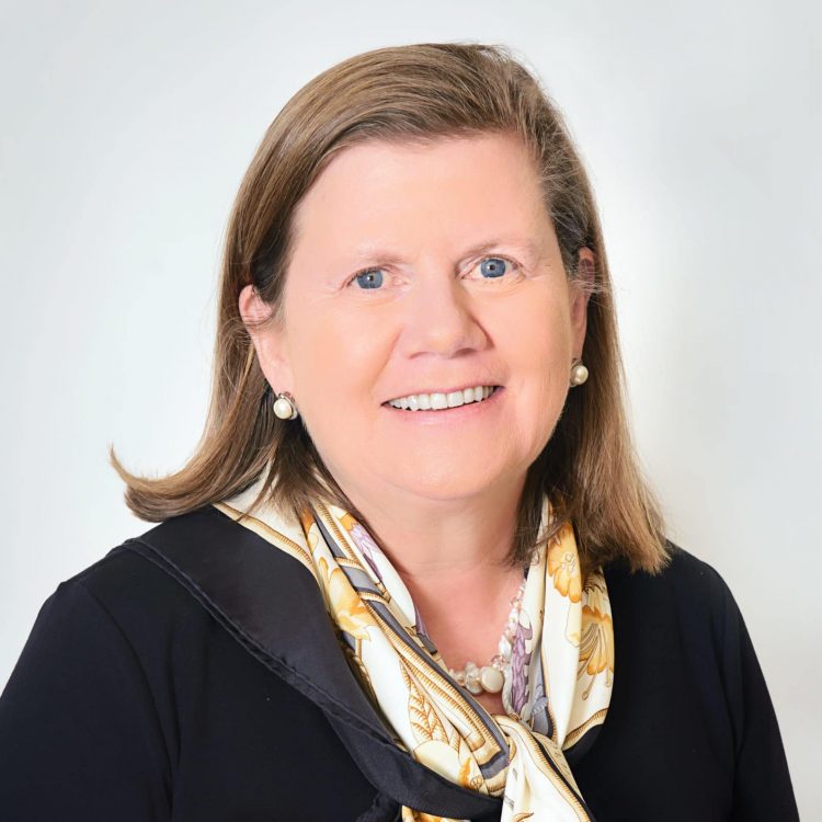 Picture of woman in a black top with a yellow and white patterned silk scarf